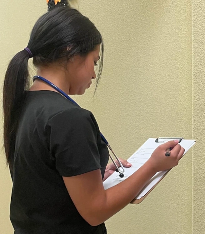 {{ school.name }} student reviewing patient paperwork {{ school.name }} student reviewing patient paperwork