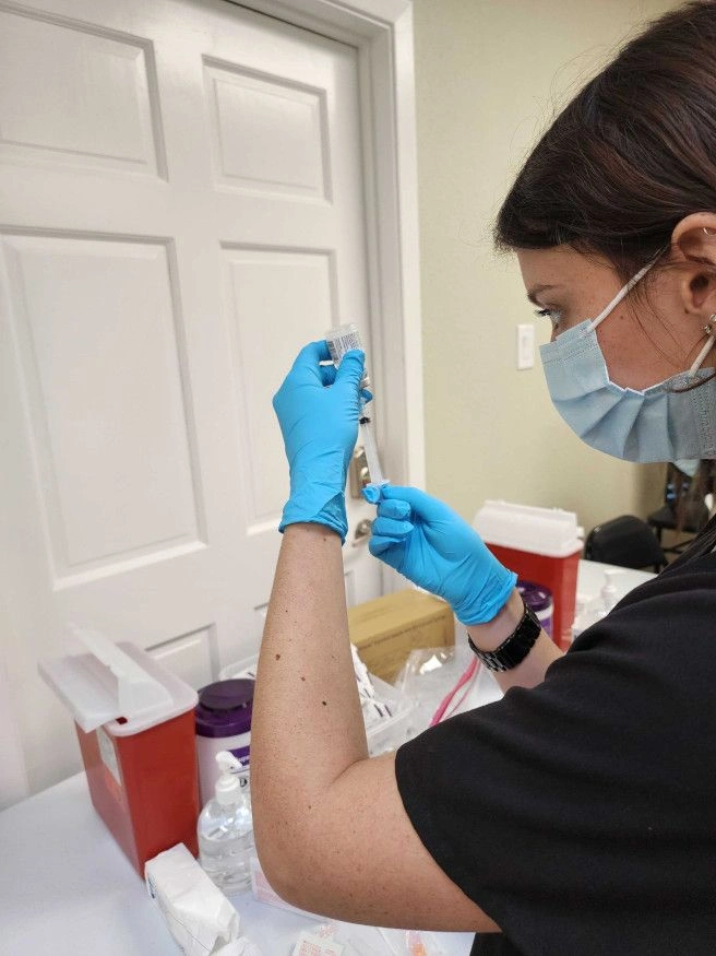 {{ school.name }} student drawing liquid from vial {{ school.name }} student drawing liquid from vial