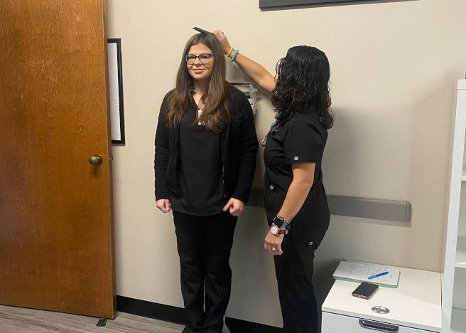 {{ school.name }} student measuring the height of another student {{ school.name }} student measuring the height of another student