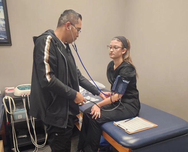 {{ school.name }} student taking another student's blood pressure {{ school.name }} student taking another student's blood pressure