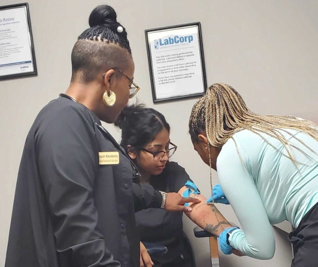 {{ school.name }} students training to take blood draws with their instructor nearby {{ school.name }} students training to take blood draws with their instructor nearby