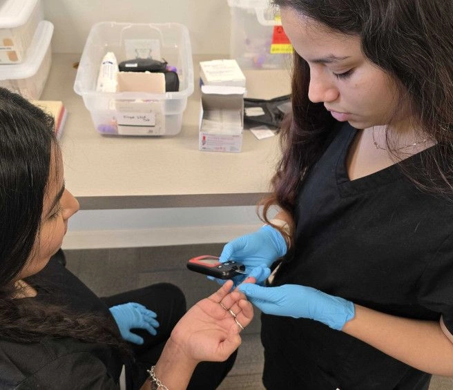 {{ school.name }} student training to take blood from a finger prick {{ school.name }} student training to take blood from a finger prick