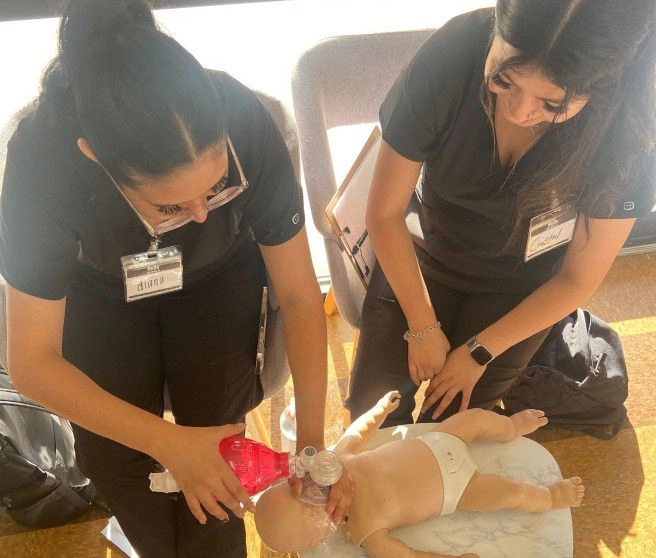 {{ school.name }} students performing CPR on test infant dummy {{ school.name }} students performing CPR on test infant dummy